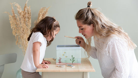Mum and daughter play Little Dutch's Fishing Game, sat together at a table.
